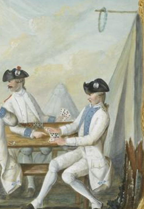 Three soldiers dressed in white uniforms play cards at a table in front of a white tent