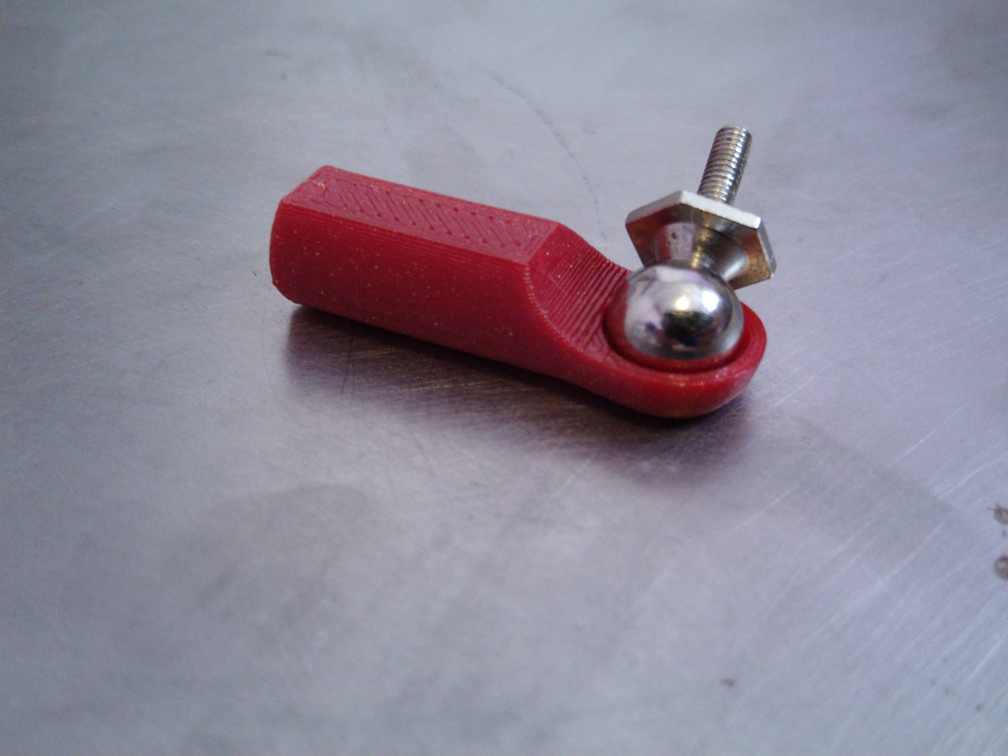 Printed red ball-cup rod end, with machined steel 3/8" ball and mounting interface sitting in the ball cup