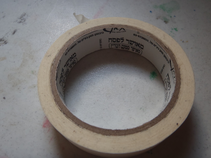 Masking tape. The inside of the roll is printed with Hebrew information, including "*Me-ushar lepesach: me-ushar mita'am habada"tz*"