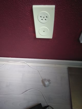 the same wall socket, now unplugged, showing a socket for a four pronged plug