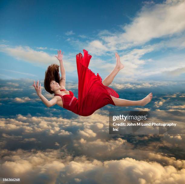 Woman in flowy red dress falling from the sky