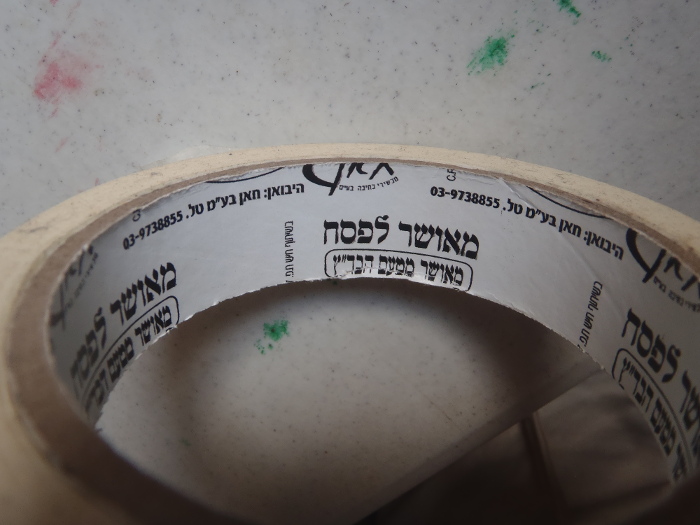 Masking tape. The inside of the roll is printed with Hebrew information, including "*Me-ushar lepesach: me-ushar mita'am habada"tz*"