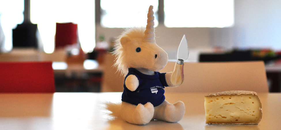 Unicorn holding knife from cheese overflow 2018 set next to a piece of cheese