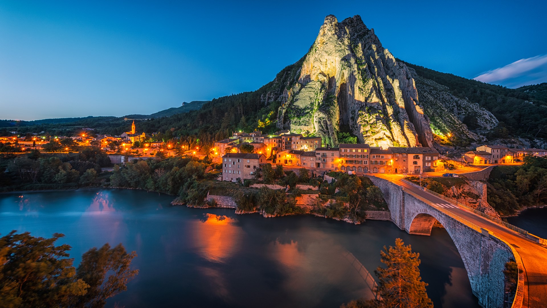 High rock stands over french village connected by stone bridge over river