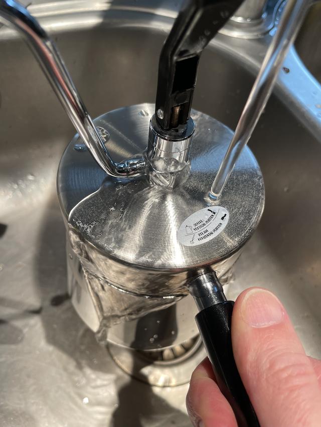 A stovetop coffee maker being run under cold water