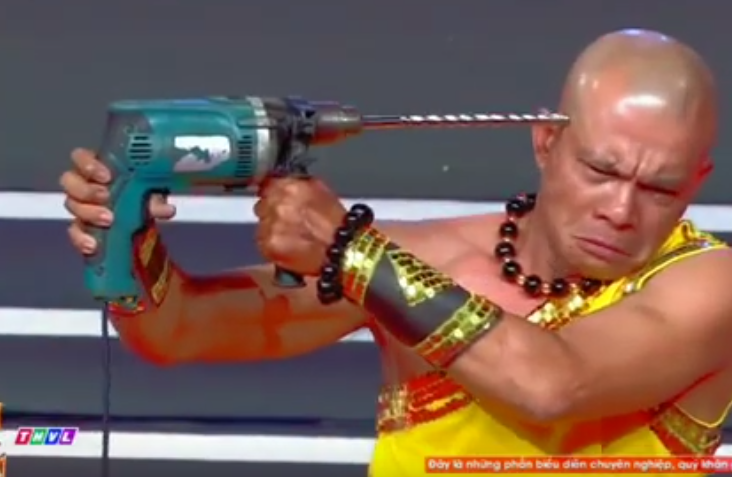 monk using two hands to mock-press a drill onto their head