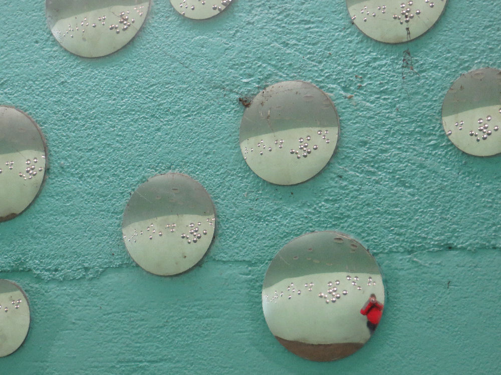 A wall with little round mirrors, a person in one of them