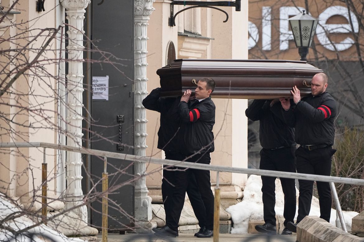 Four Russian men with red and black armbands carrying a coffin