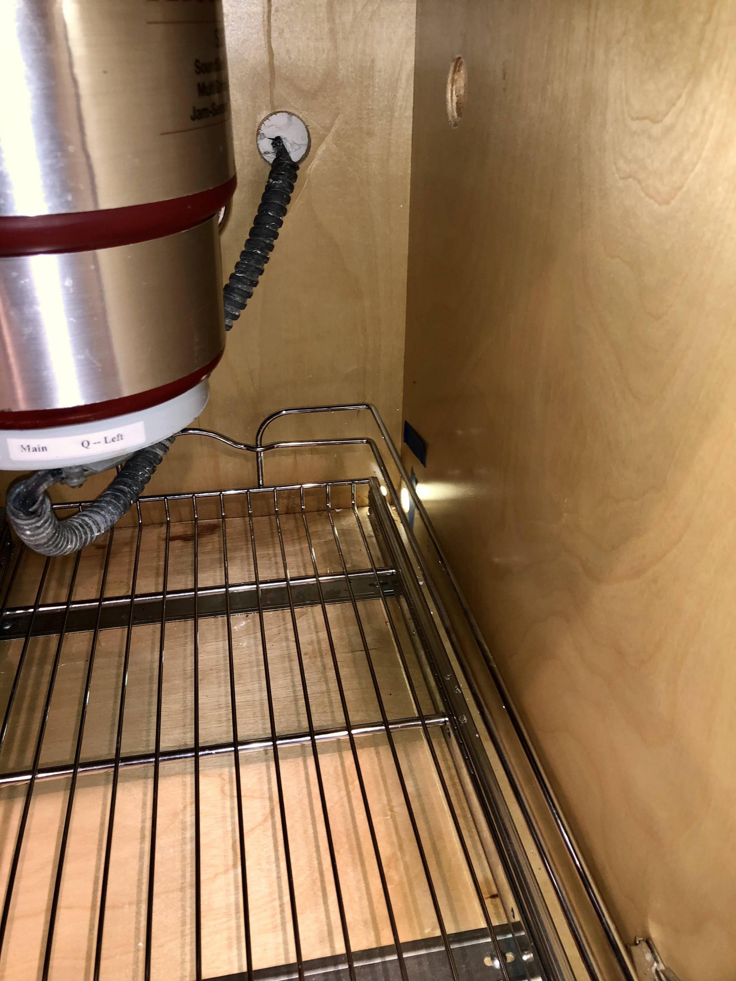 Sink cabinet with slide out shelf, right side shows exiting holes for previous dishwasher