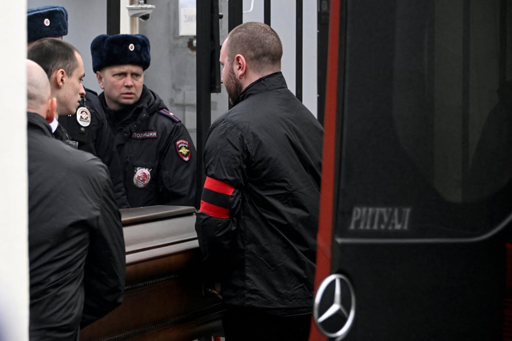 A Russian man wearing a red and black armband speaks with a military official