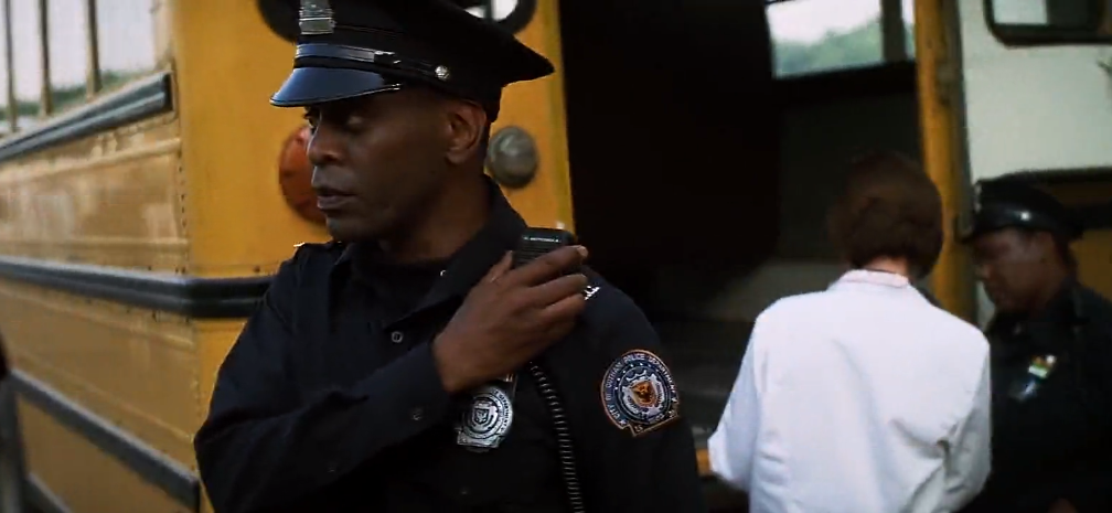 person getting on a yellow bus, guarded by police officers