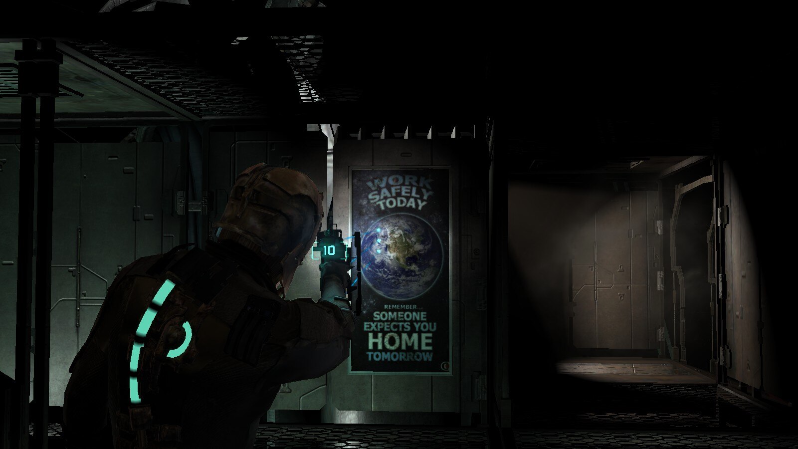 A screenshot of the original Dead Space game which was released in 2008. Isaac is aiming at a poster, displaying planet Earth, with the aforementioned message written on it.