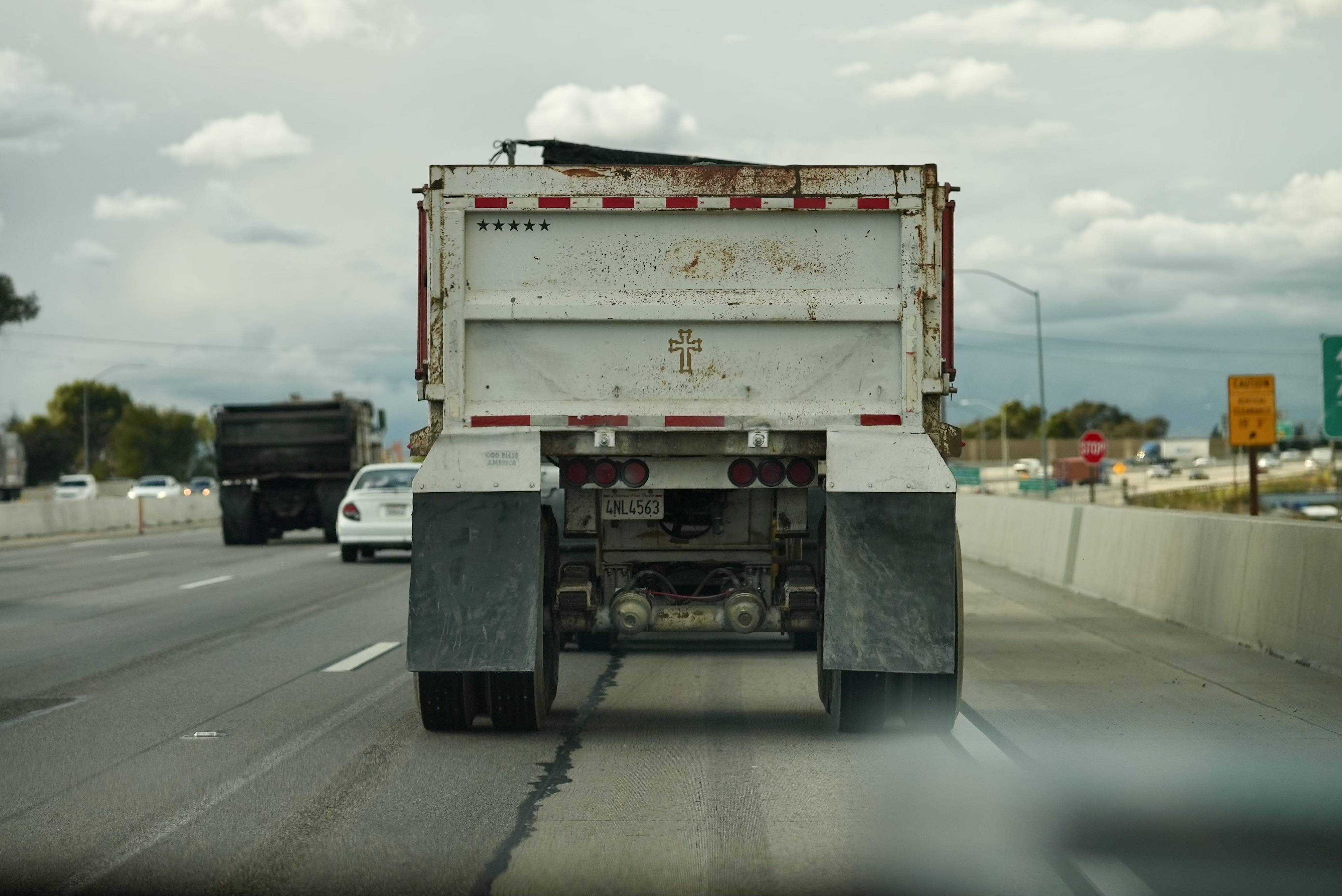 Truck on a highway bearing a cross in the back.