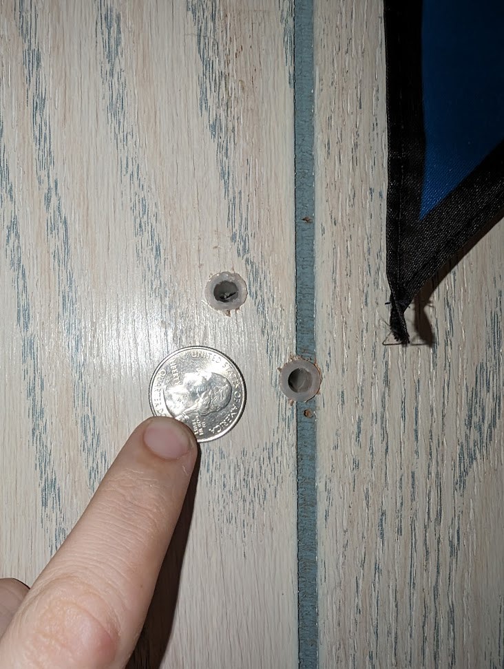 close-up of drilled holes in wood paneling with drywall anchors