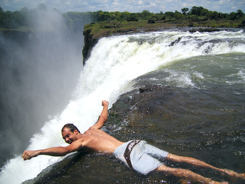 People bathing at the top of a waterfall