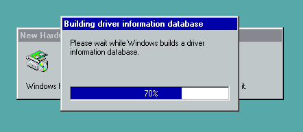 A screenshot of Windows 98 showing an active window without any buttons, entitled “Building driver information database”, with text inside “Please wait while Windows builds a driver information database.” and a progress bar at 70%. Behind it there is a notification window informing of new hardware being detected.