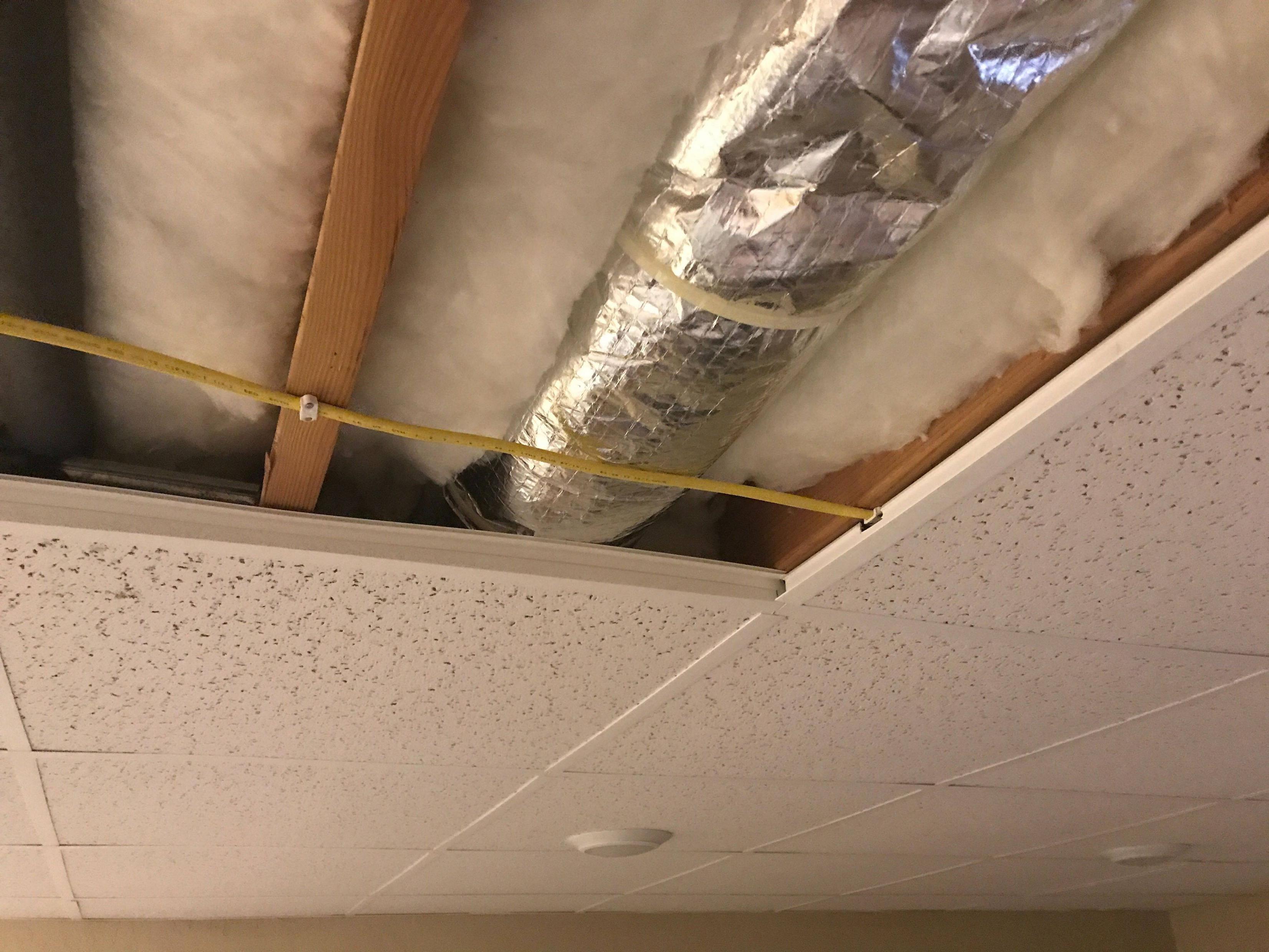 Photo of ceiling tile grid with some tiles removed so that the "surface mount" nature is visible.