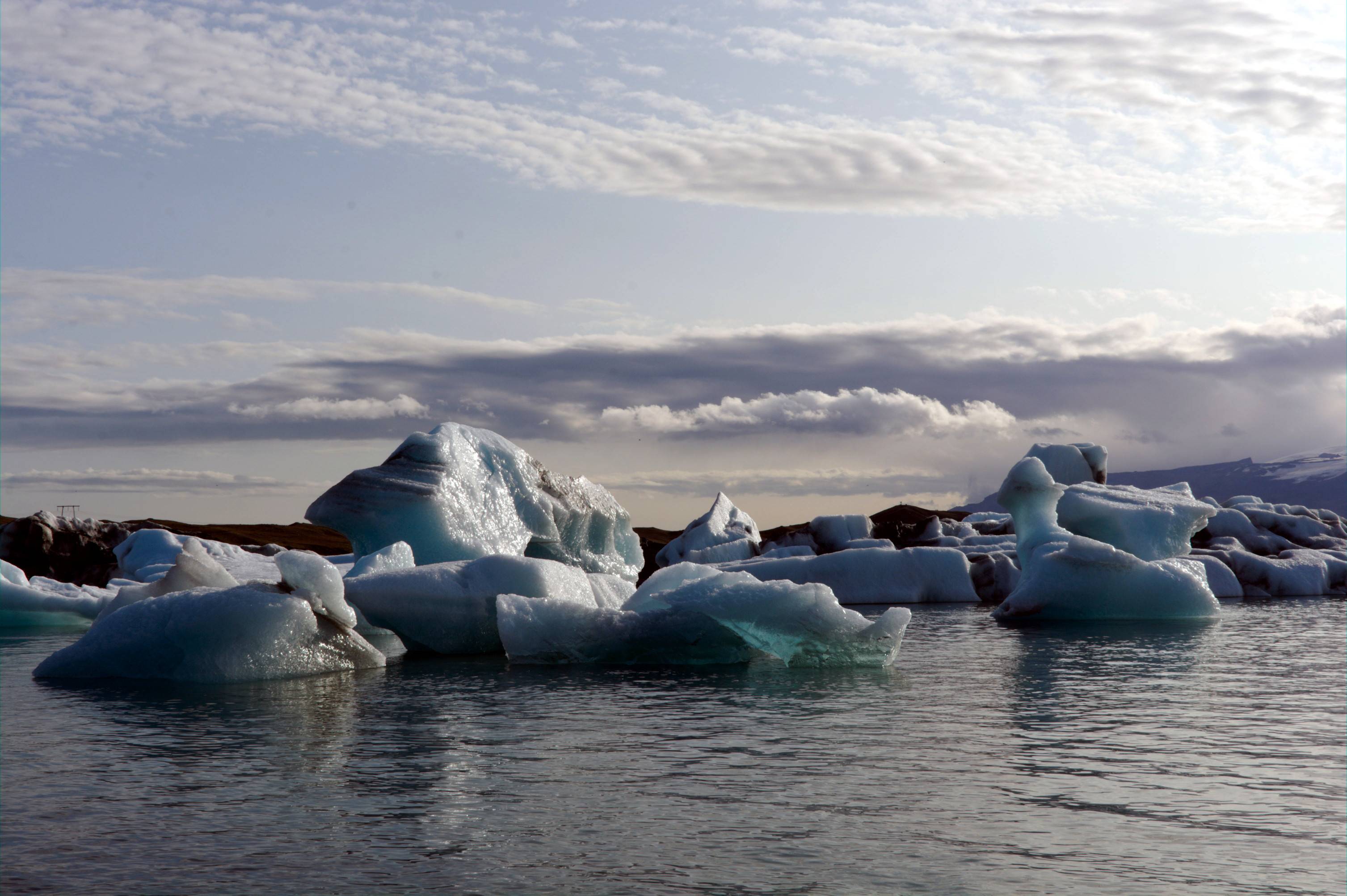 large blocks of ice floating in a lagoon, under an early evening sky