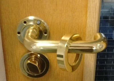 Doorhandle with decorative ring unscrewed revealing screws