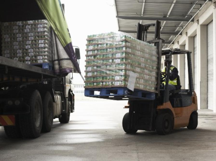 Photo of a forklift loading a pallet of goods onto a truck