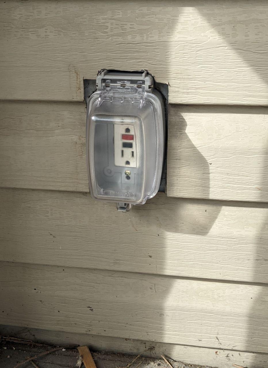 a picture of the new plug cover, showing the gap between the original square cutout in the vinyl siding and the new plug cover