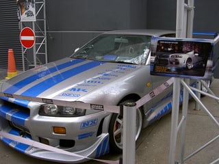 Silver Nissan Skyline with blue detailing and logos, prop as used in the movie "2 Fast 2 Furious" on display at a show