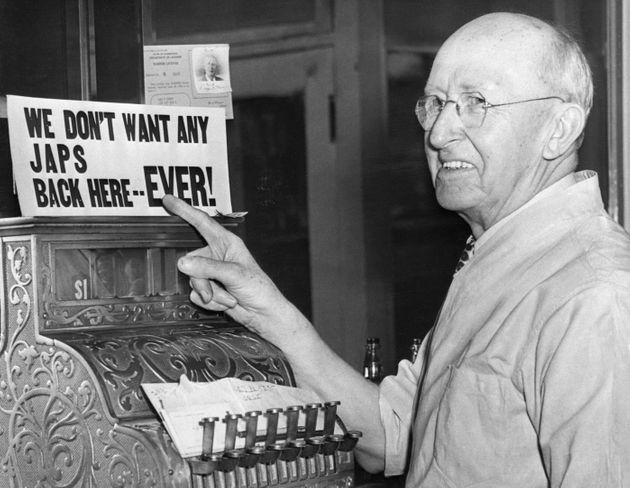 Man pointing to "We don't want any japs back here... ever!" sign above cash register