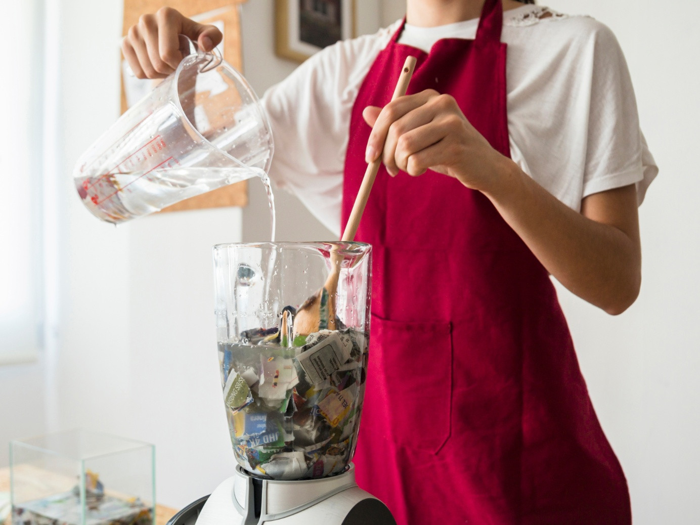 A person putting scraps of paper and a large amount of water into a kitchen blender. Will it blend?