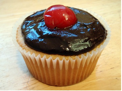 Boston cream cupcake topped by a cherry