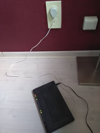 a router, a black rectangular box, connected to a wall socket