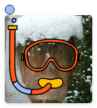 A moai-shaped flowerpot with a layer of snow on top and a pair of goggles