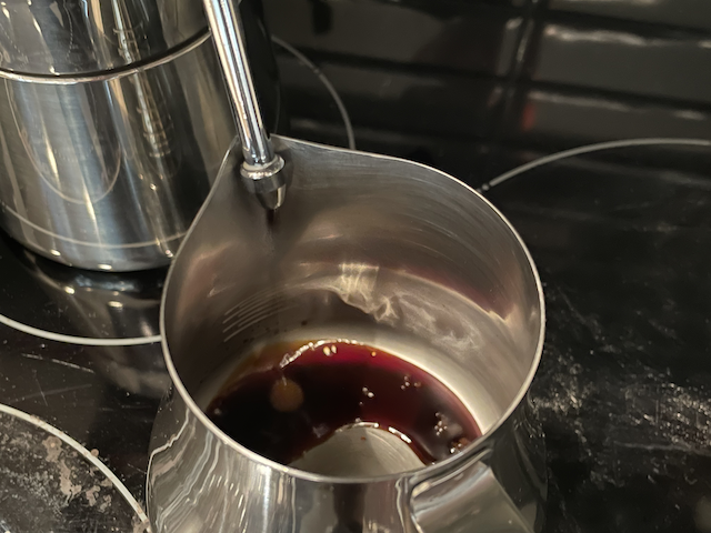 A stovetop coffee maker brewing some coffee into a pitcher