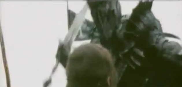 Sauron's head and shoulders loom above the back of Aragorn's head, his right arm and sword drawn back to swing