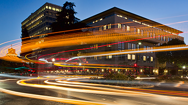 A large well-lit city bus turns a downtown street corner