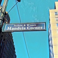 A commemorative street sign affixed to a lamppost at a street corner, dedicated to Nelson and Winnie Mandela