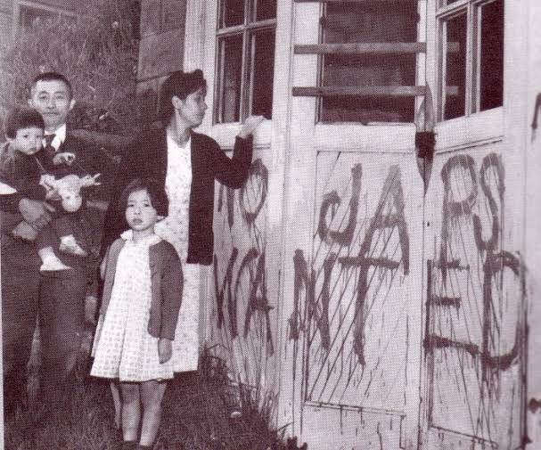 Japanese family standing in front of house with "No japs wanted" graffiti