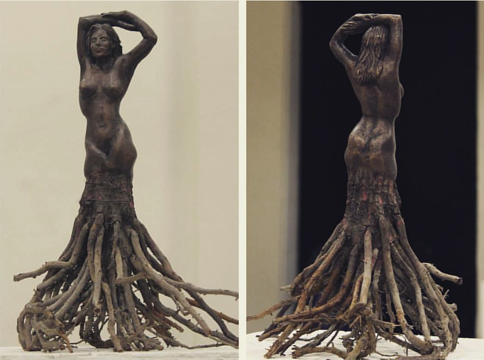 A carved wooden sculpture of a human woman where the wood transitions into the carved plant's roots around mid thigh, replacing the lower leg and foot