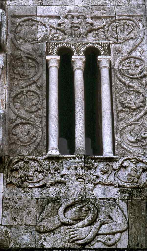 Satan tricephalos-tonguesticker, with fiery crown or hair, holding the Serpent, on the amazing 12th century façade at Tuscania (Viterbo).