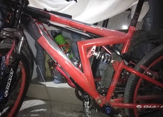 A red MTB with black accents. Most notable, the tube in line with the seat post shows a gap (for the suspension), with the tube completing the triangle bent forward in a sharp angle.