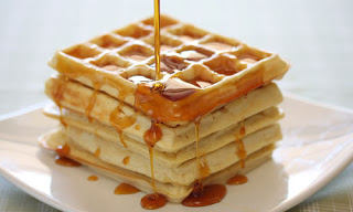 stack of waffles with maple syrup being poured