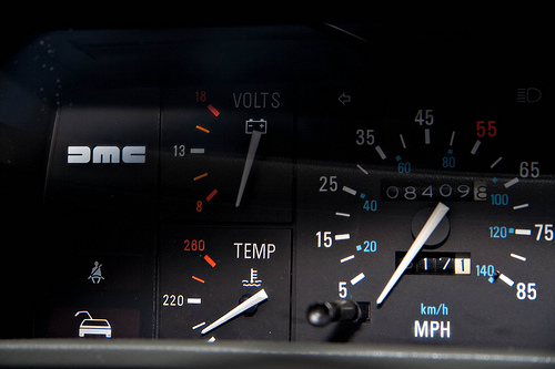 A picture of a DeLorean dashboard; the dial speedometer goes up to 85mph / 140kph.