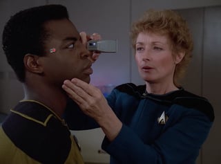 Image of Dr. Pulaski examining Geordi's eyes, from "Star Trek: The Next Generation" S02E05.