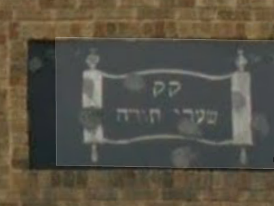 Aged synagogue sign, saying, in Hebrew, the letter 'qof' twice, followed by "*Shaaray Torah*".