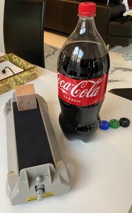 Image of the cap cutouts (different nozzle shapes), next to the coke bottle and dynamics cart upon which it was placed horizontally