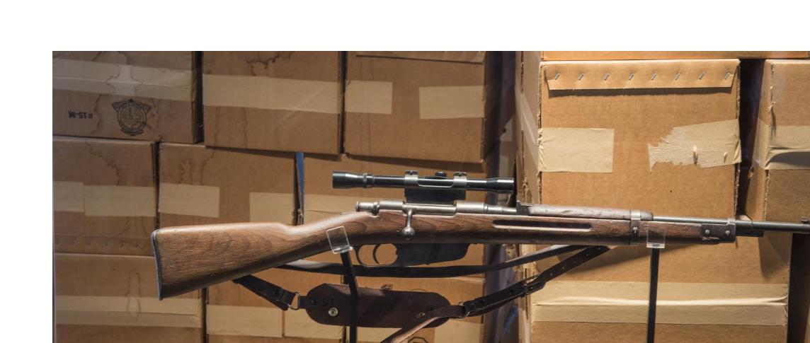 Picture of a replica of Oswald's rifle in front of a stack of boxes