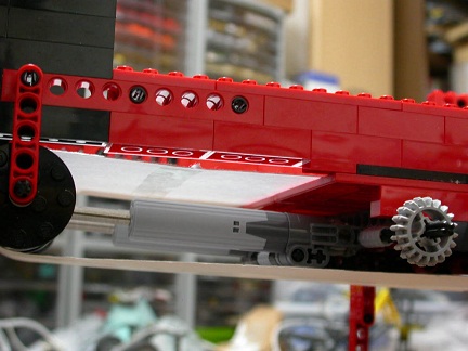 low-angle shot up into the tensioning mechanism of a paper conveyor belt in a LEGO model